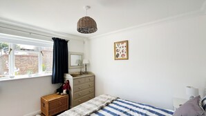 Une chambre à coucher comprenant un lit, une commode, une fenêtre et un élément décoratif mural.