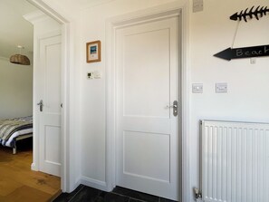 Habitació amb dues portes blanques, un quadre petit al mur, un termòstat i un senyal que indica la platja.