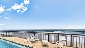 A poolside area with lounge chairs and a view of the ocean. - Ocean Trillium 803 - a 1 bedroom condo with beautiful ocean views (New Smyrna Beach)