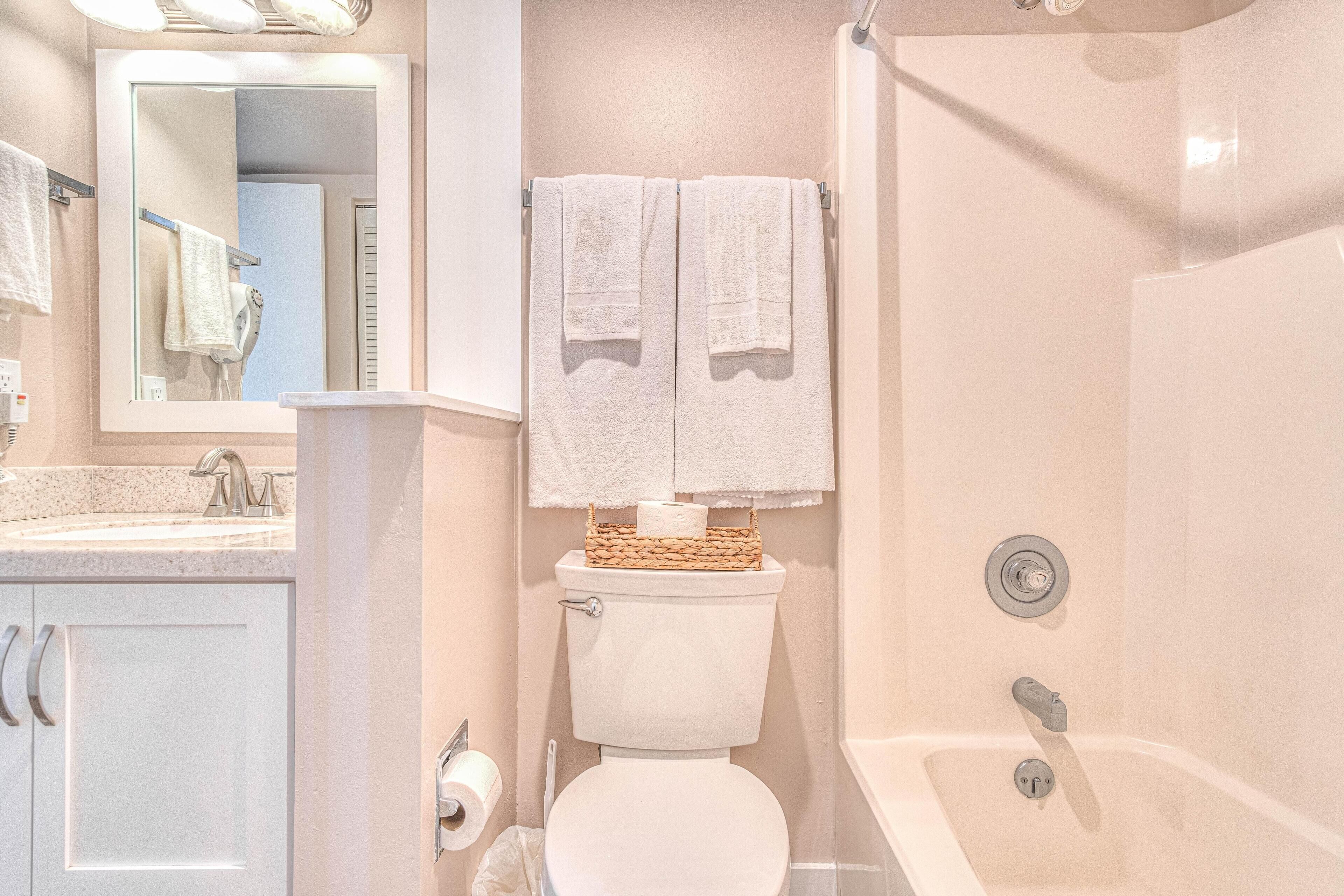 Une salle de bain comprenant des toilettes, un lavabo, un miroir et une baignoire.