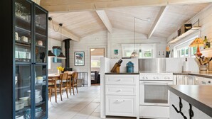 Una cocina moderna con armarios blancos, un horno Bosch y un comedor con una mesa y sillas de madera.