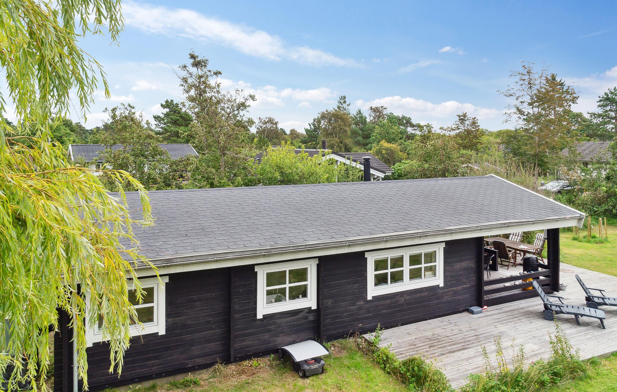 A black building with a sloped roof, a covered porch, and a deck with chairs.