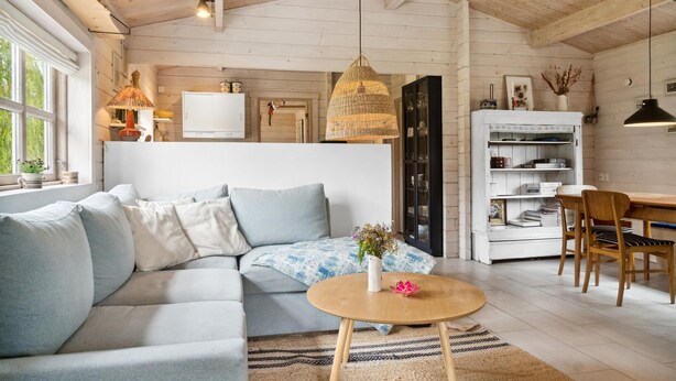 Un salón acogedor con un sofá azul claro, una mesa de centro redonda de madera y una estantería.