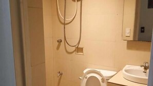 Un baño pequeño con inodoro, lavamanos y ducha.