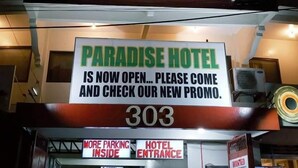 Exterior del Hotel Paraíso, con un cartel que indica que está abierto y promociona una nueva oferta.