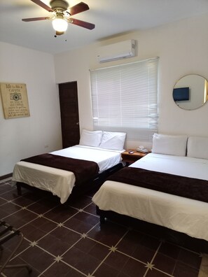 A hotel room with two beds, a ceiling fan, an air conditioning unit, a window with blinds, a bedside table with a phone, and a wall with a motivational quote. - Loft MN960 Mty centro cerca de todo (Monterrey)