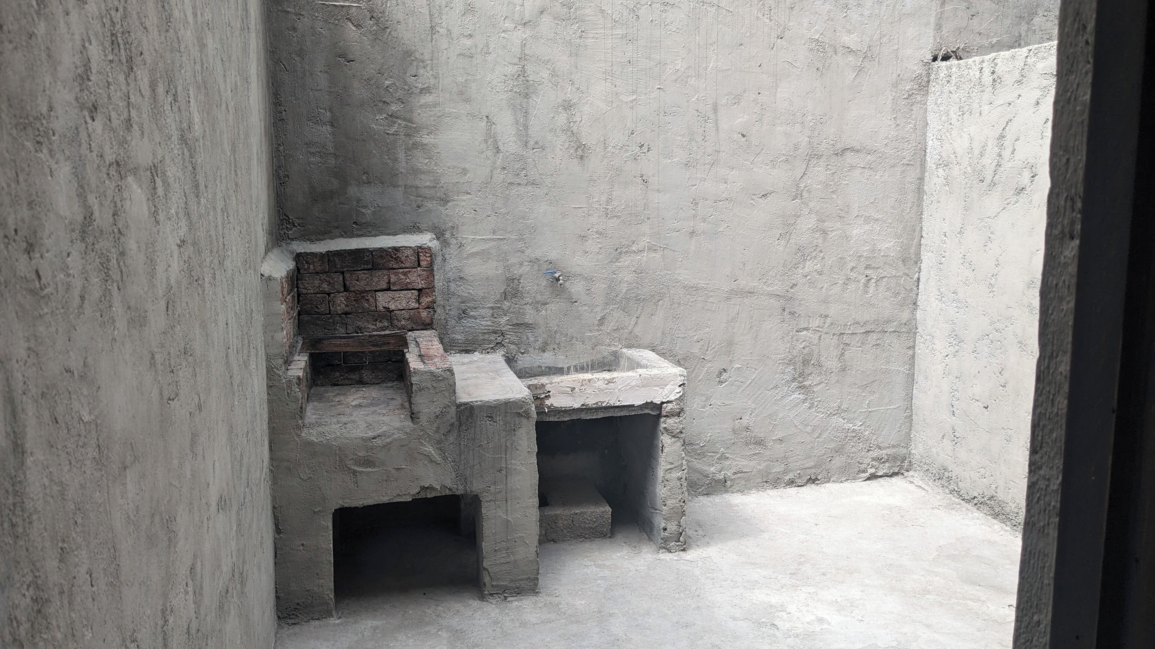 A small, enclosed space with a brick fireplace and a concrete bench.