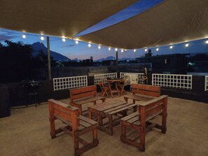 An outdoor patio with wooden furniture and string lights, overlooking a cityscape with mountains in the background. - Loft MN960 Mty centro cerca de todo (Monterrey)