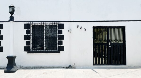 A white building with a black gate and a window with black bars. - Loft MN960 Mty centro cerca de todo (Monterrey)