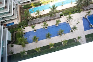 A rooftop pool area with multiple swimming pools, palm trees, and lounge chairs. - U-GO Edificio Morros Ultra (Cartagena)