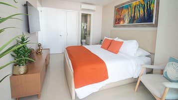 Habitación de hotel con cama, escritorio, silla, televisor y un cuadro en la pared.