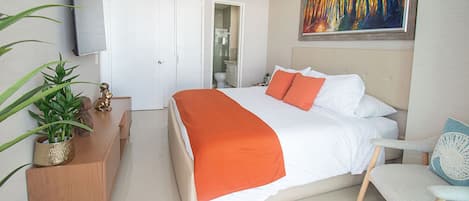 A hotel room with a bed, a desk, a chair, a TV, and a painting on the wall.