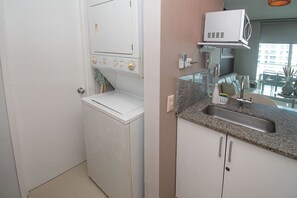 Eine kompakte Küche mit Waschmaschine, Mikrowelle und Spüle mit Granitarbeitsplatte.