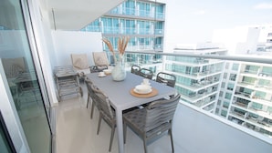 A modern dining area with a glass balustrade, a table set with plates, cups, and a vase with pampas grass. - U-GO Edificio Morros Ultra (Cartagena)