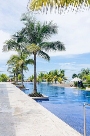 A pool area with palm trees and lounge chairs. - U-GO Edificio Morros Ultra (Cartagena)