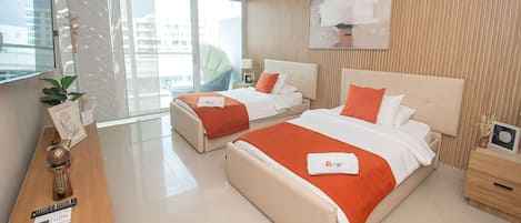Habitación de hotel con dos camas, televisión, escritorio y vistas a la ciudad.