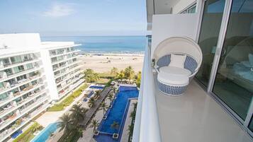 Un balcón con vista a la playa y una piscina.