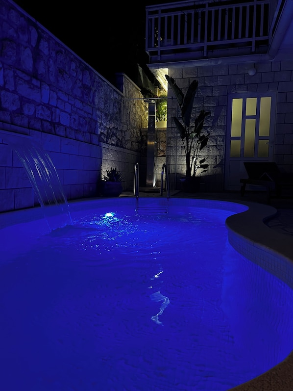 A swimming pool with a stone wall and a small waterfall feature.