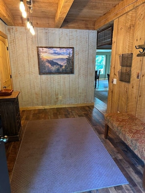 A room with wooden walls, a large painting, a bench, and a rug.