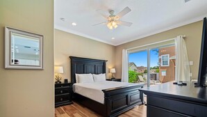 A bedroom with a large bed, a ceiling fan, a nightstand, and a dresser. - Theater Room | Games Area | Kids Themed Bedrooms | Private Pool (Kissimmee)