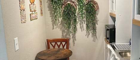 Une cuisine de taille réduite, avec une table et des chaises en bois, un réfrigérateur et des éléments décoratifs accrochés au mur.
