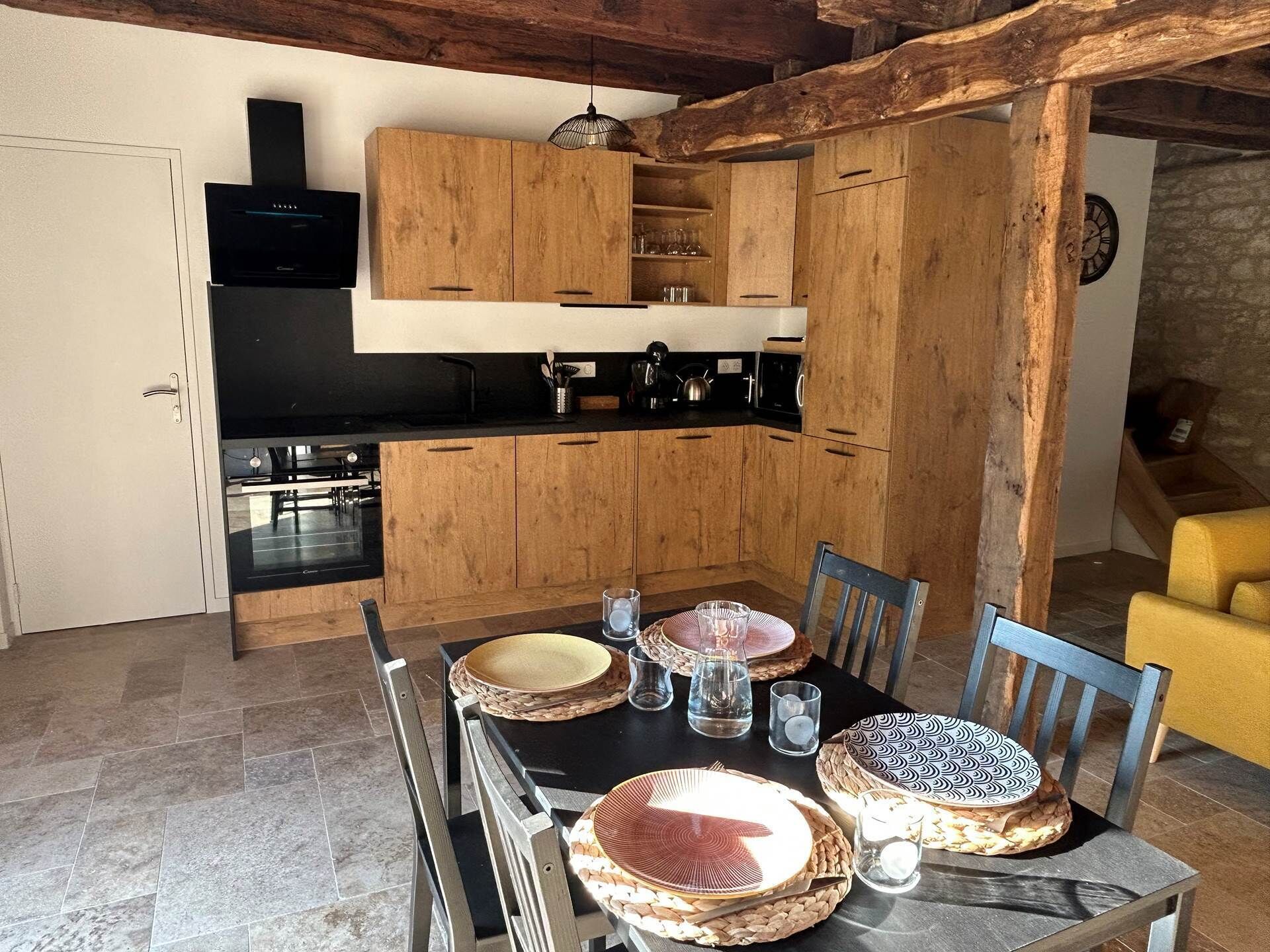 Eine moderne Küche mit Holzschränken, einem schwarzen Herd und einem Esstisch, gedeckt mit Tellern und Gläsern.