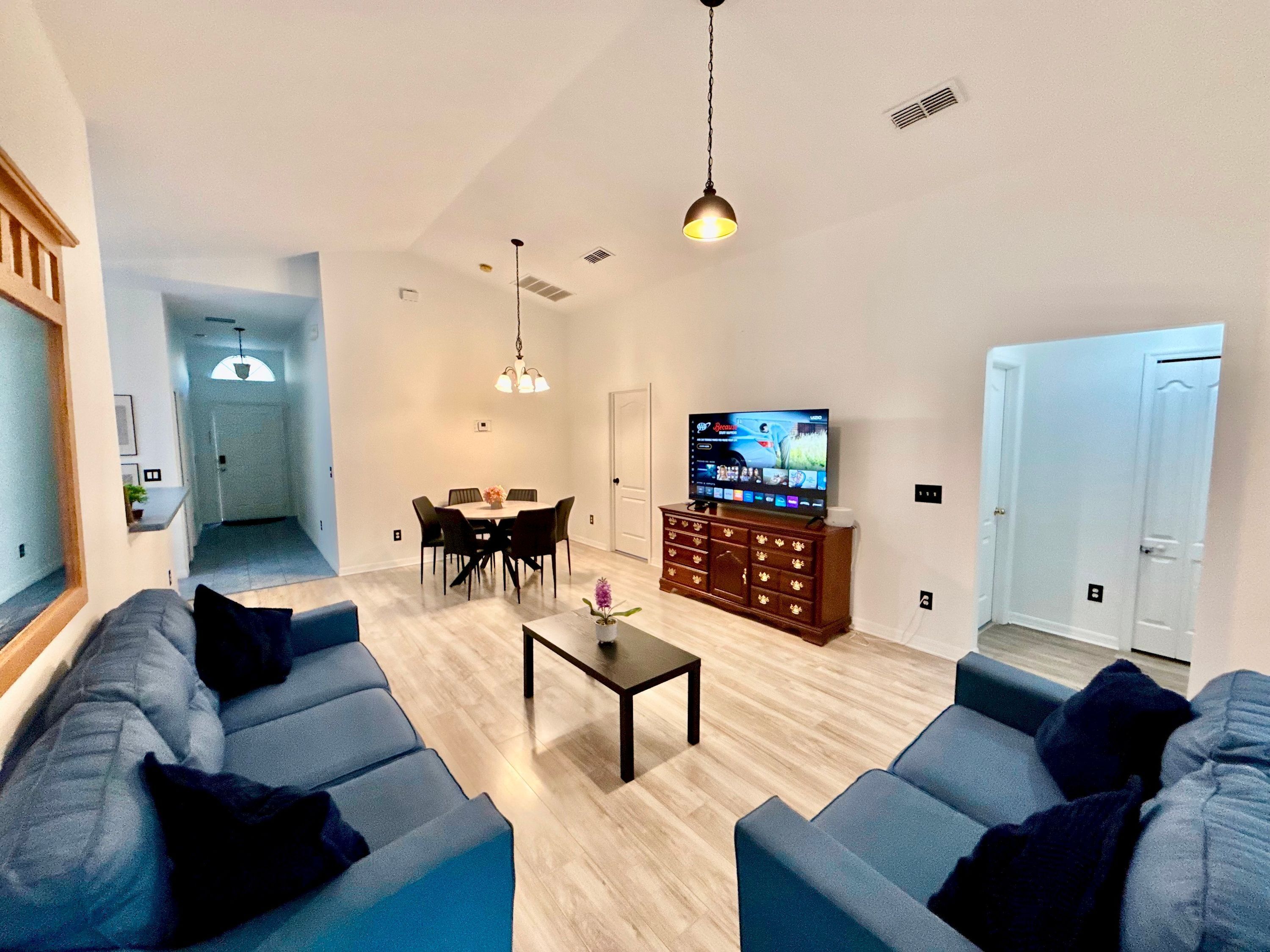 A living room with a TV, sofas, a coffee table, and a dining area.