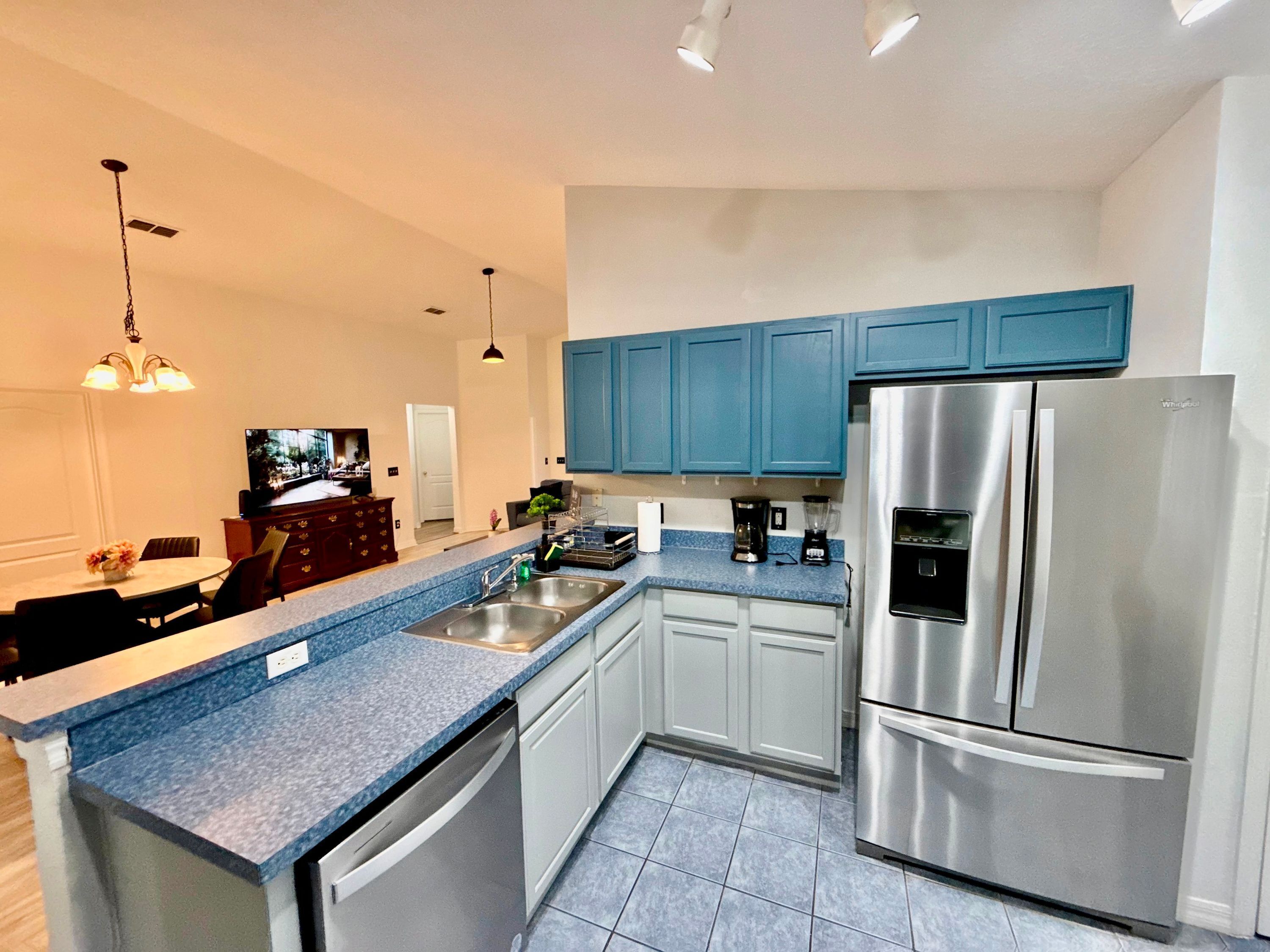 A modern kitchen with blue cabinets, stainless steel appliances, and a dishwasher.
