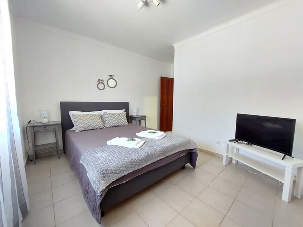 A bedroom with a bed, bedside tables, a TV, and a wardrobe.