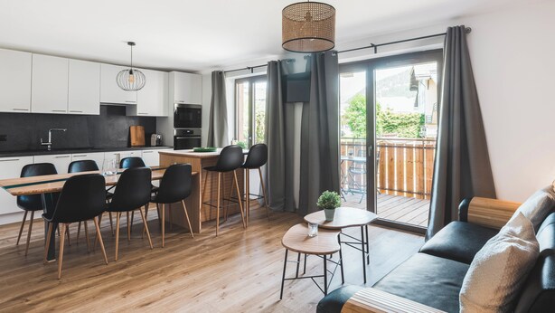 A modern apartment with a kitchen, dining area, and a balcony with a wooden deck.