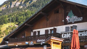 A wooden building with a sign reading "Les Sapins" and "Café".