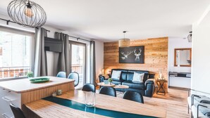 A modern living room with a wooden dining table, blue sofa, and a fireplace.