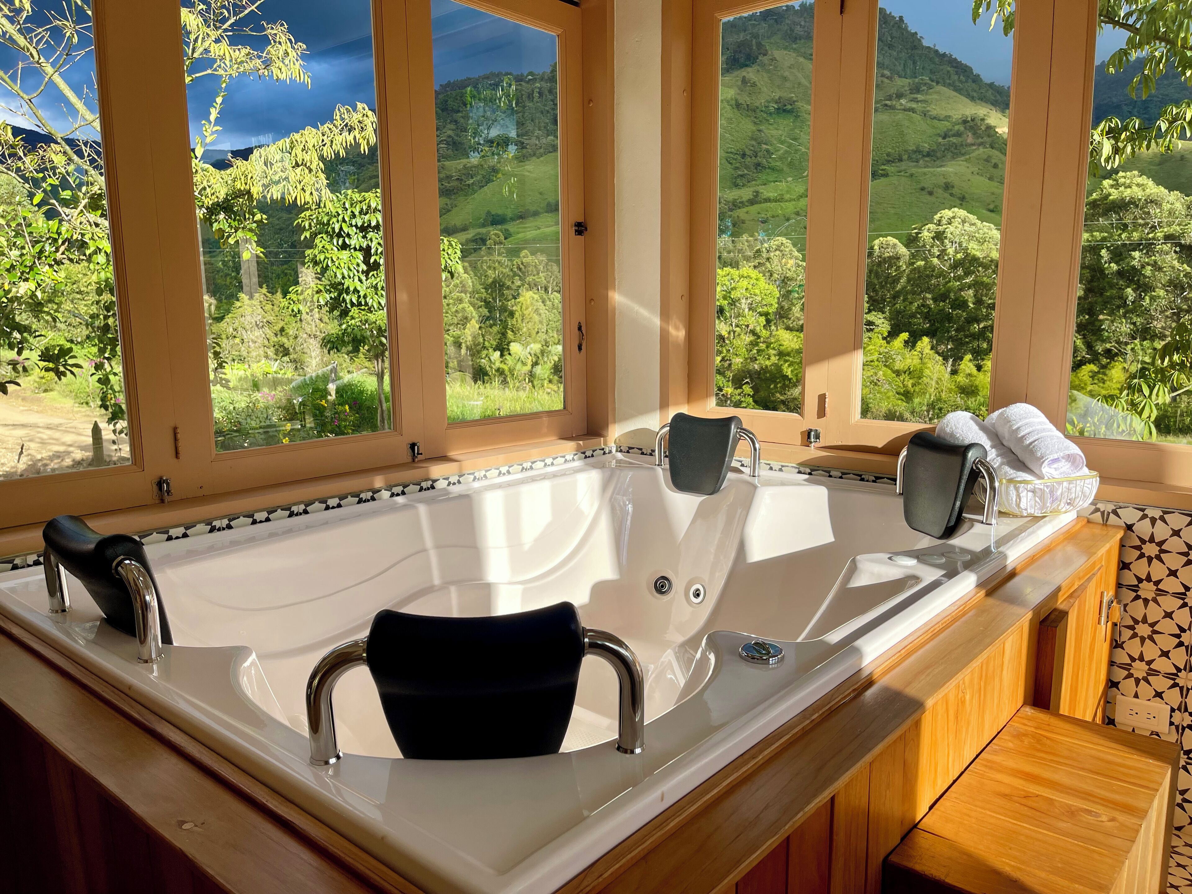 A bathroom with a large bathtub, a black chair, and a glass bowl with towels.