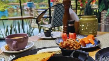 A table with a meal consisting of rice, plantains, and a small bowl of beans, set against a scenic view.