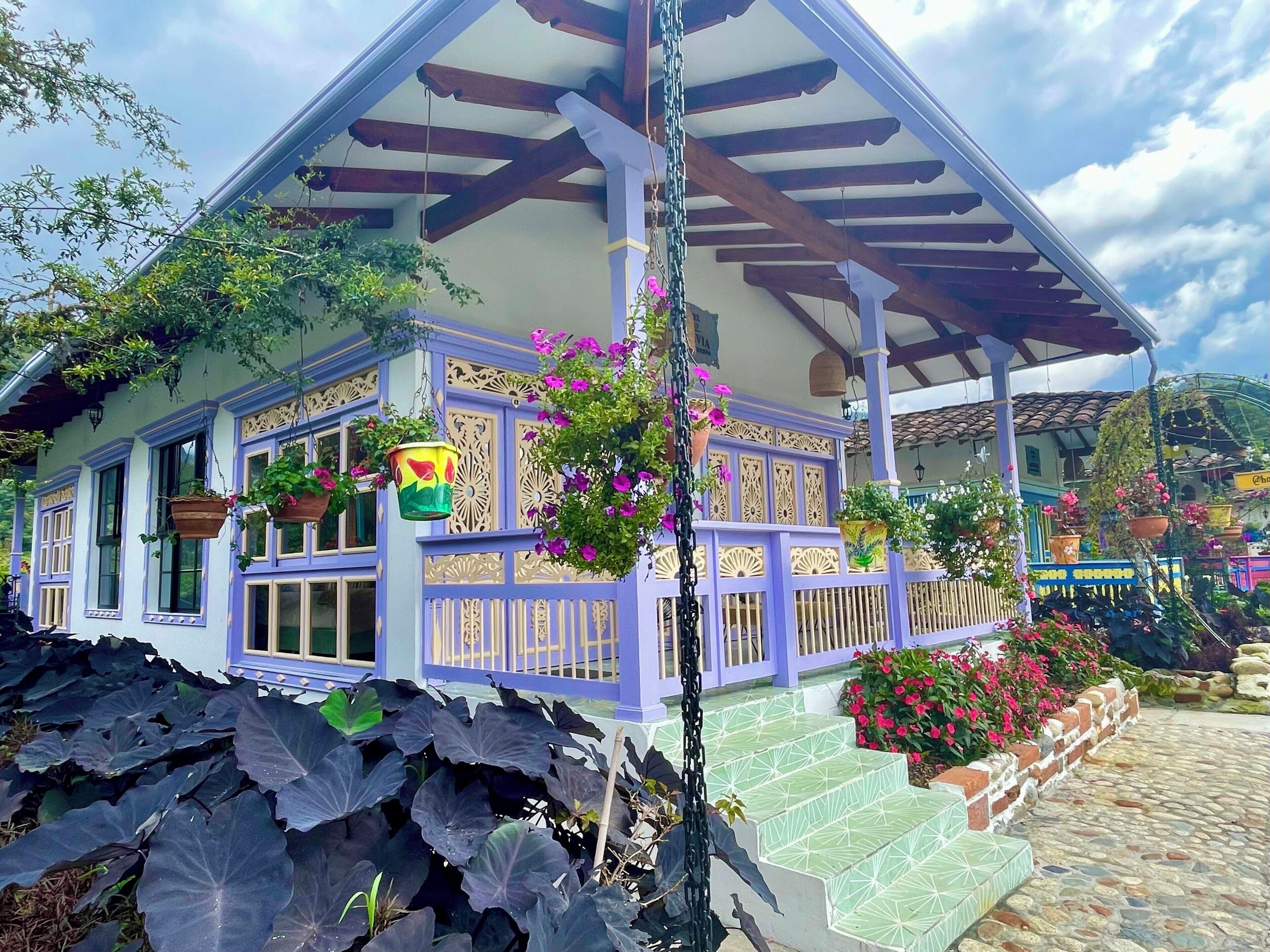 Ein Haus mit Veranda, hängenden Blumentöpfen und einem Kiesweg.