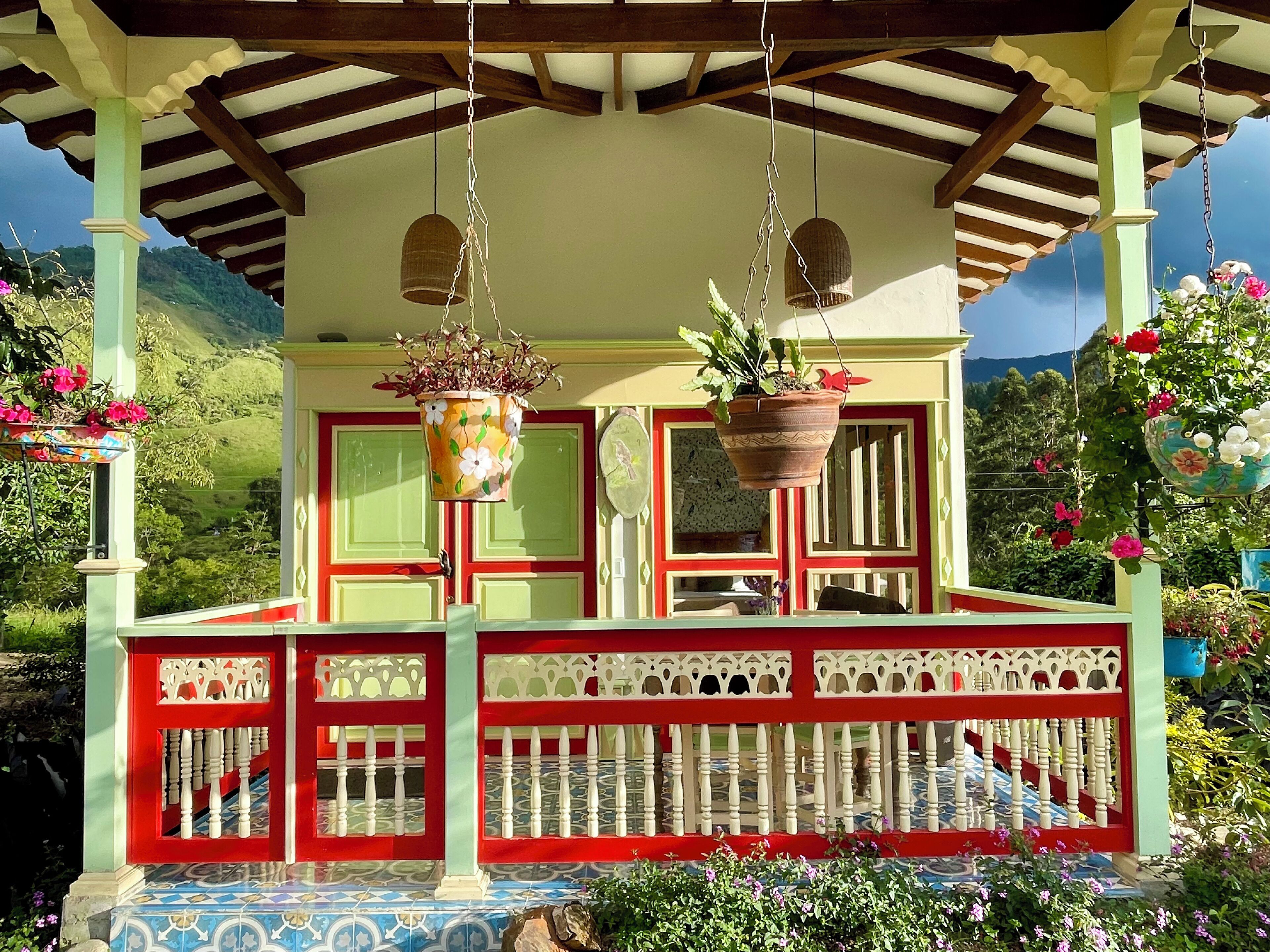 A covered porch with a tiled floor, a railing, and hanging planters with flowers.