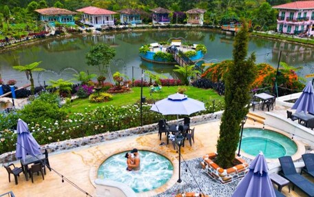 A resort with a swimming pool, lounge chairs, and a garden area.