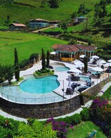 Un resort con una grande area piscina, posti a sedere all'aperto e vista sul paesaggio circostante.