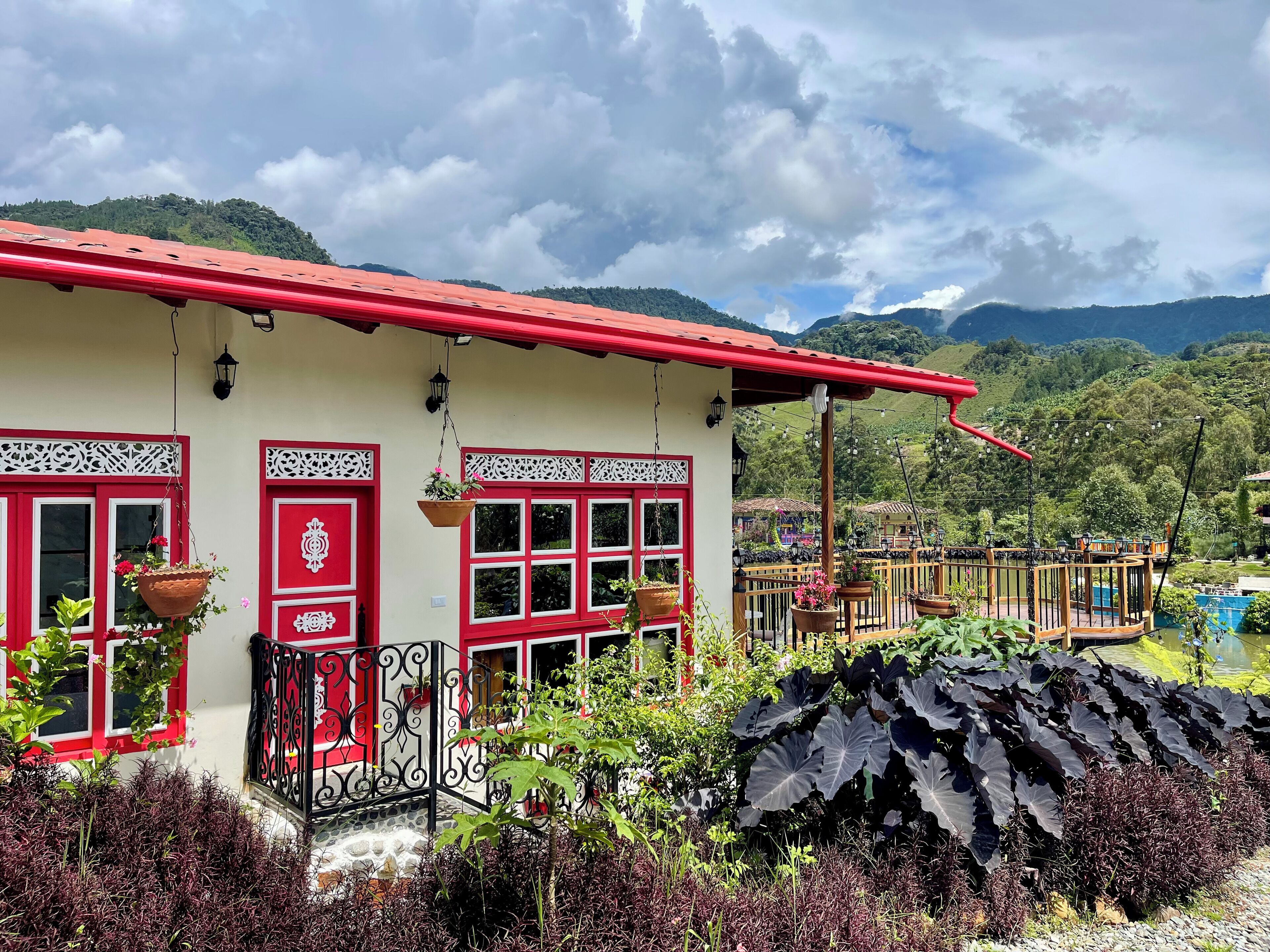 A building with red and white trim, multiple windows, and hanging planters.