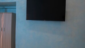 Ett rum med en ljusblå vägg, en trägarderob och en väggmonterad platt-TV.