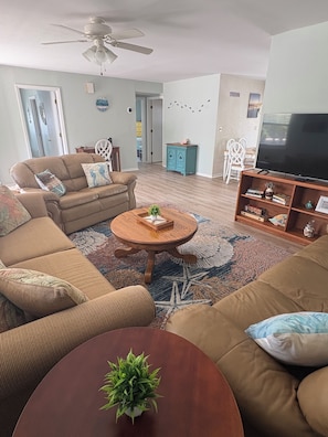 A living room with a sofa, a coffee table, a TV stand, and a ceiling fan.