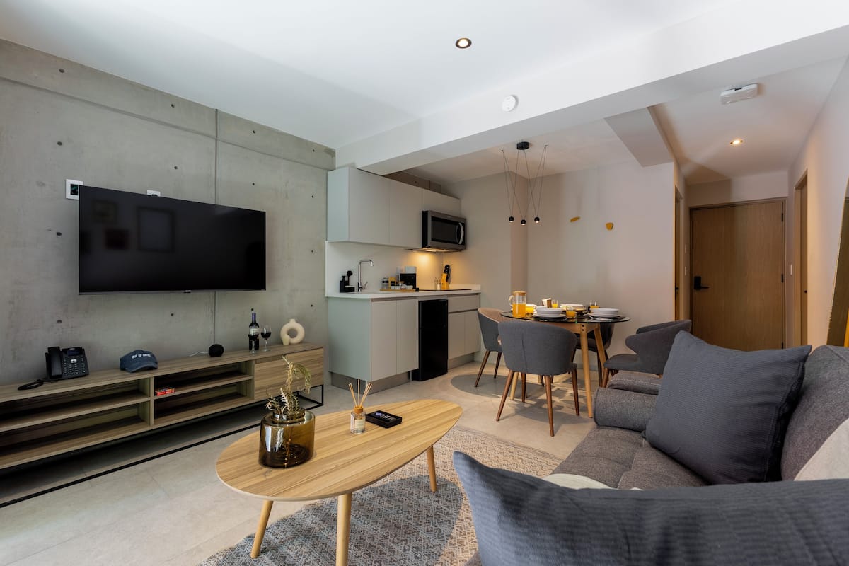 Una sala de estar moderna con televisor de pantalla plana, comedor y cocina.