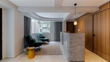 Un interno moderno con una reception, poltrone verdi e un'ampia finestra con tende.