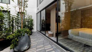 Una habitación de hotel moderna con un ventanal grande, una cama y una planta en maceta.