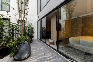 Une chambre d’hôtel moderne avec une grande fenêtre, un lit et une plante en pot.