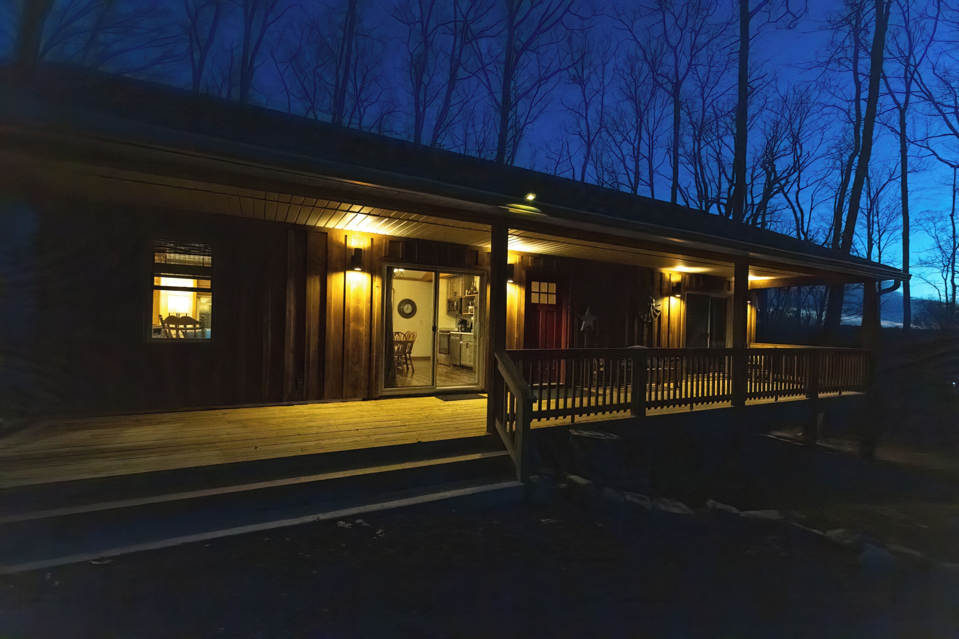 A wooden cabin with a porch, a visible kitchen area, and a door leading to the interior.