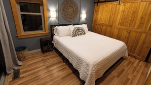 A bedroom with a large bed, a wooden wardrobe, a window with blinds, and two wall-mounted lamps. - Boho Getaway for Two, Stay near the New River Gorge and Glade Creek Farm (Cool Ridge)