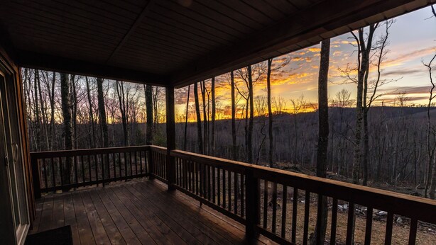 A wooden deck with a railing overlooking a forested area during sunset. - Boho Getaway for Two, Stay near the New River Gorge and Glade Creek Farm (Cool Ridge)