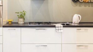 A modern kitchen with white cabinets, a stainless steel range hood, and a glass shelf with decorative items. - Casa Roma nel cuore di Palermo by Wonderful Italy (Palermo)