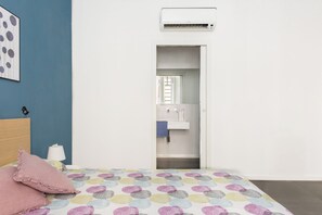 A bedroom with a bed, pillows, a wall-mounted air conditioner, and a bathroom visible through an open door. - Casa Roma nel cuore di Palermo by Wonderful Italy (Palermo)